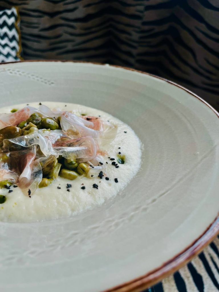 Plato gourmet con habitas baby crema de esparragos blancos y velo de papada iberica